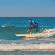 perfekt position på liten grön våg surfstudent håller stabil hållning på brädan medan hen surfar en liten ren våg