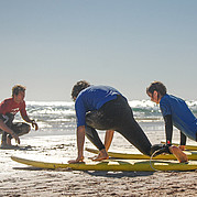träning av take-off på land under surfkurs surfcoach visar hur man gör en korrekt take-off på stranden innan eleverna går i vattnet