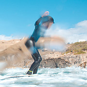 första take-off på surfbrädan barn reser sig upp på surfbrädan och fångar en liten våg under surfkursen