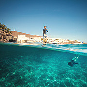 SUP i det varma blå vatten från klippan och strandpromenaden